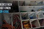 Schublade mit 3D-gedruckten Gridfinity-Faechern, jedes Fach mit QR-Code-Etikett, darin sortierte Elektronikbauteile